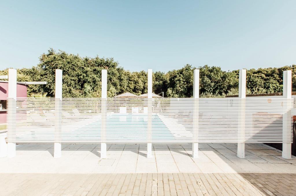 a white bench on a sidewalk with trees in the background at Suite 106 in Vasto