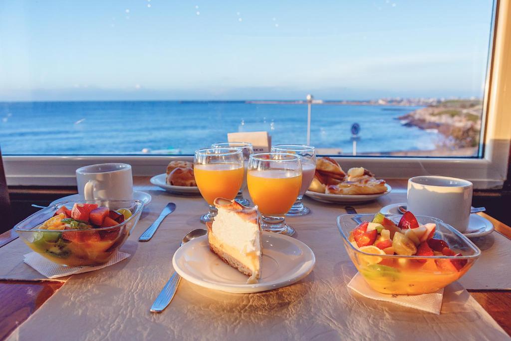 una mesa con comida y bebida y vistas al océano en Hotel Las Rocas en Mar del Plata