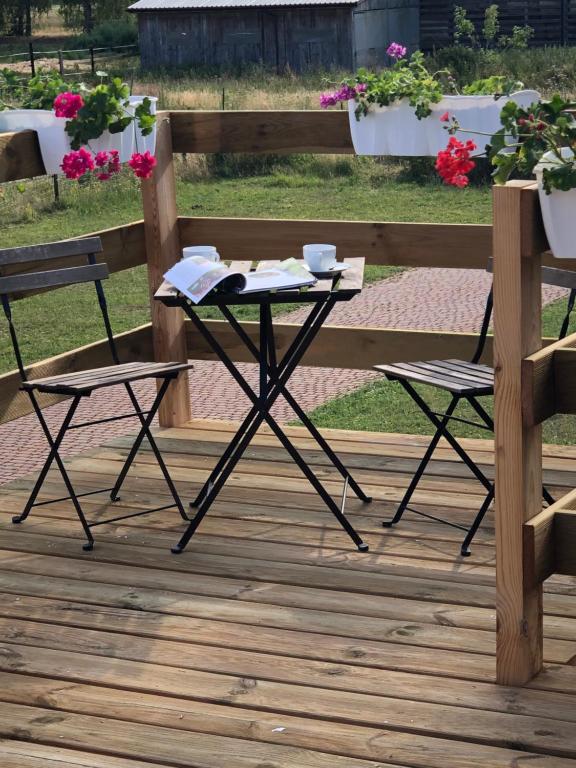 a table and two chairs on a deck with a bench at Apartamenty Brzózki in Brzózki