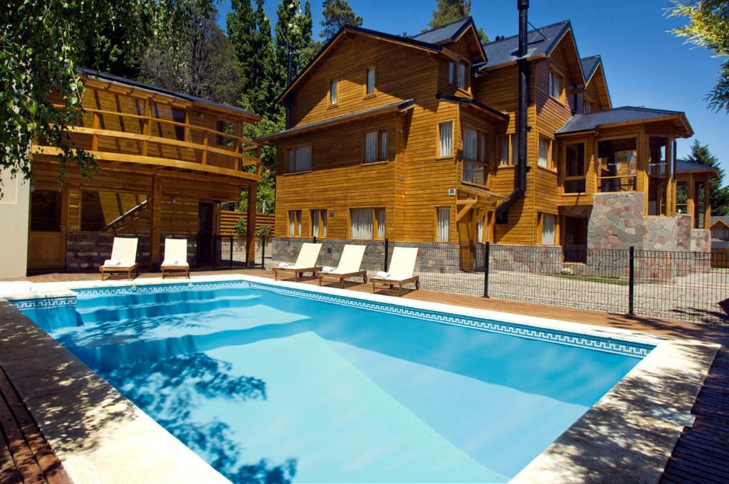 a swimming pool in front of a house at Apart Hotel Le Temps Des Cerises in San Martín de los Andes