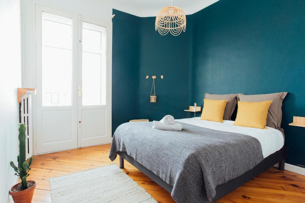 une chambre avec un grand lit avec un mur bleu dans l'établissement Coachella Vintage Chic in the Heart of St Charles Biarritz, à Biarritz