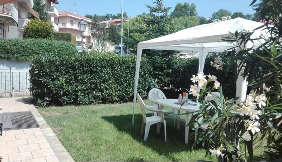 uma mesa branca e uma cadeira debaixo de um guarda-chuva num quintal em 1 La fisarmonica del Conero em Castelfidardo