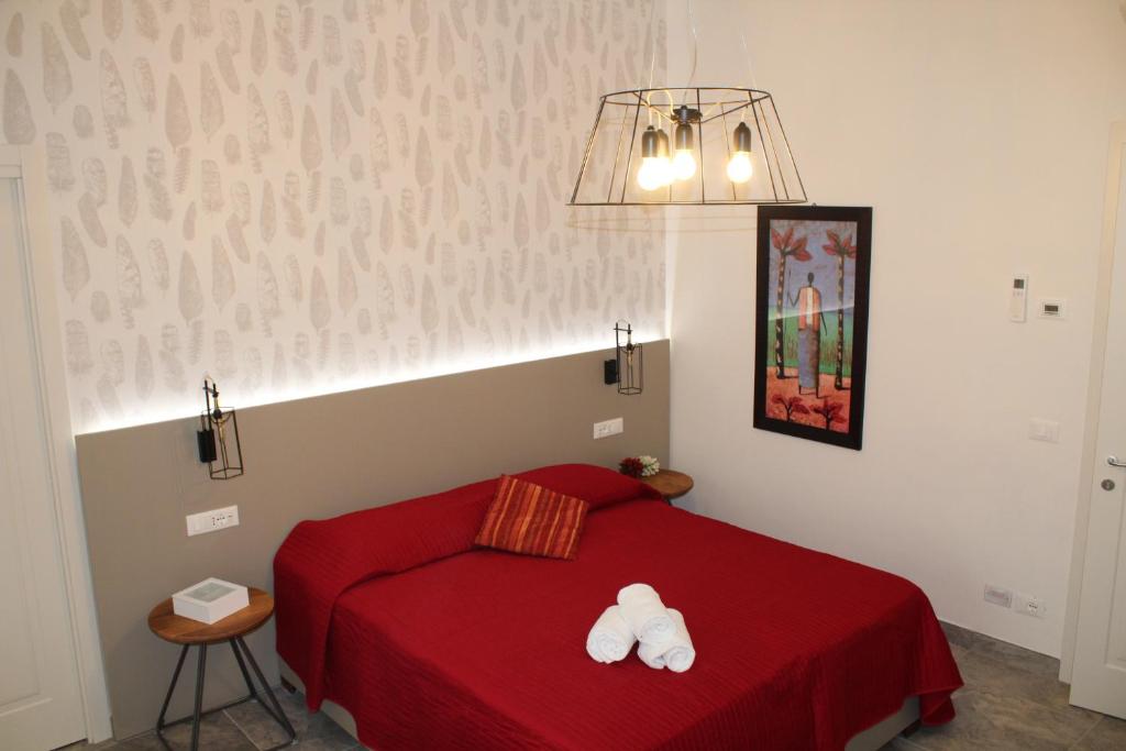 1 dormitorio con 1 cama roja y 2 toallas blancas en B&B Poggiobonizio, en Poggibonsi