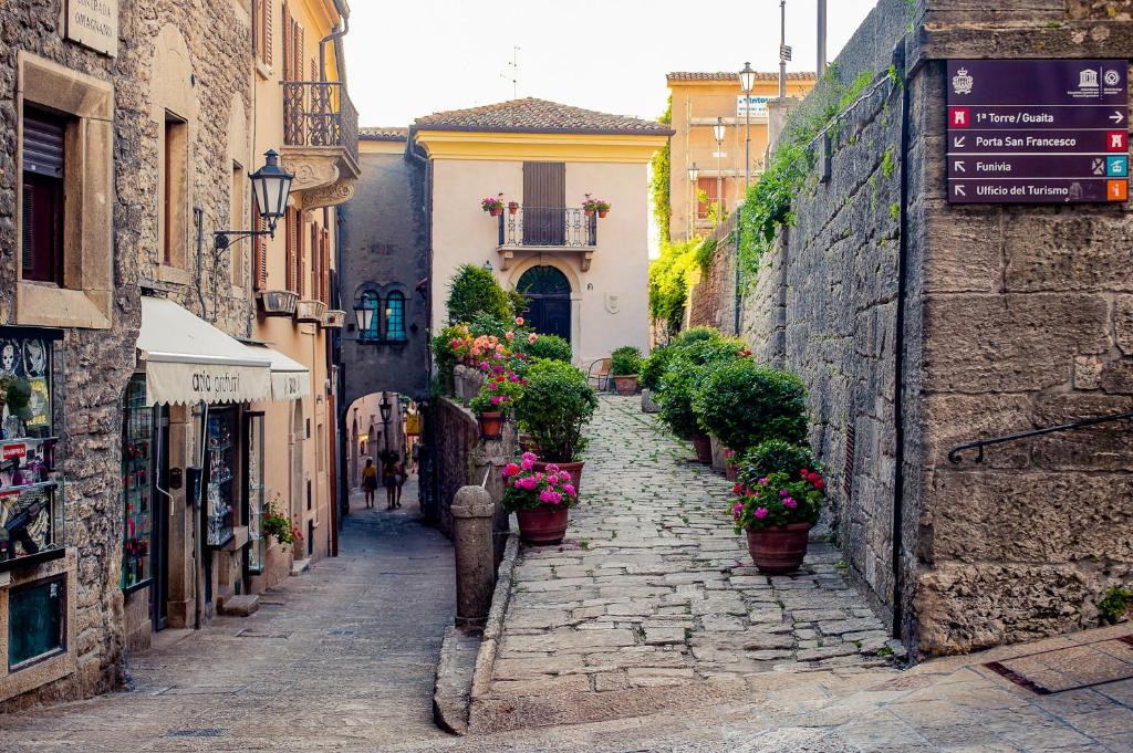 Une allée dans une vieille ville avec des plantes en pot dans l'établissement antica bifora rsm, à Saint-Marin