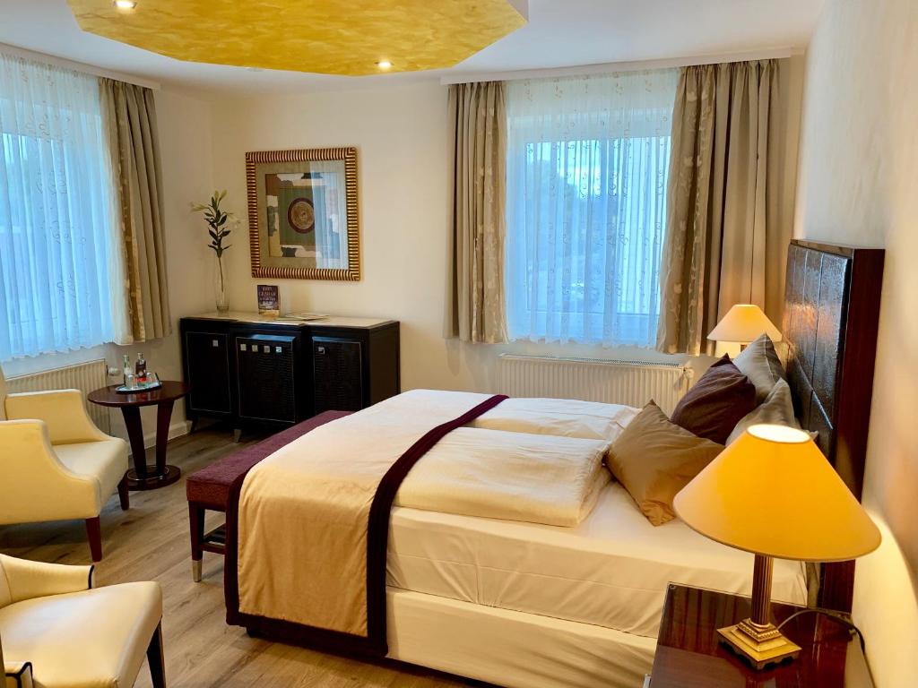 a bedroom with a large bed in a room with windows at Boutique Hotel Goldene Henne in Wolfsburg