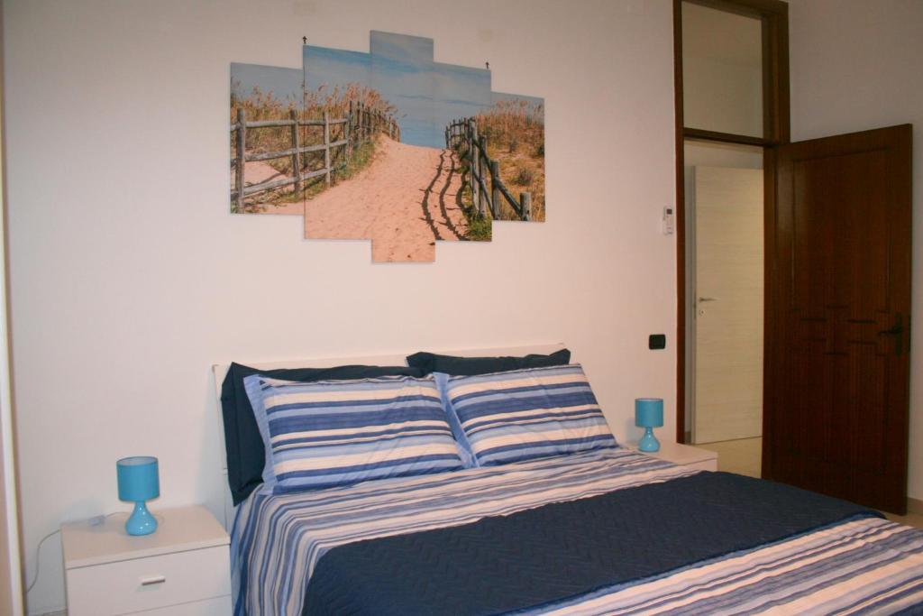 una camera da letto con un letto e due dipinti alle pareti di App.ti nel cuore di Porto Cesareo a Porto Cesareo