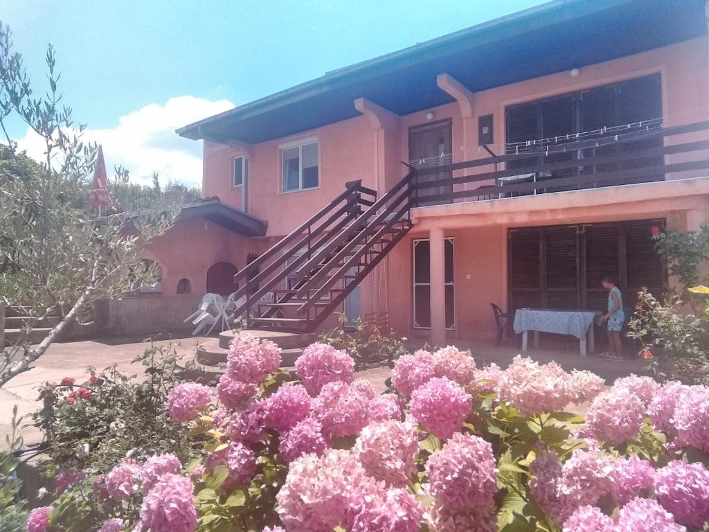a woman standing in front of a house with pink flowers at Apartmani Sofija in Nov Dojran