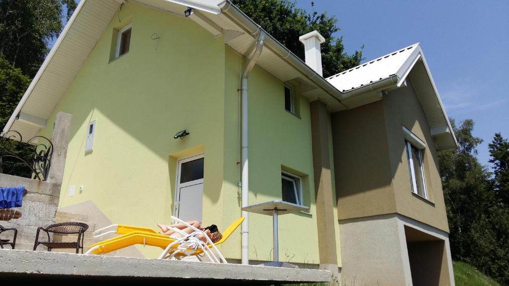a person sitting in a chair in front of a house at Holiday home Ajla in Visoko