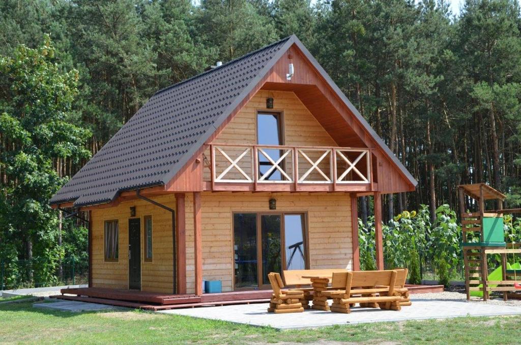 a small cabin with a black roof and benches at Sosenka 6 - całoroczne domki rekreacyjne in Milicz