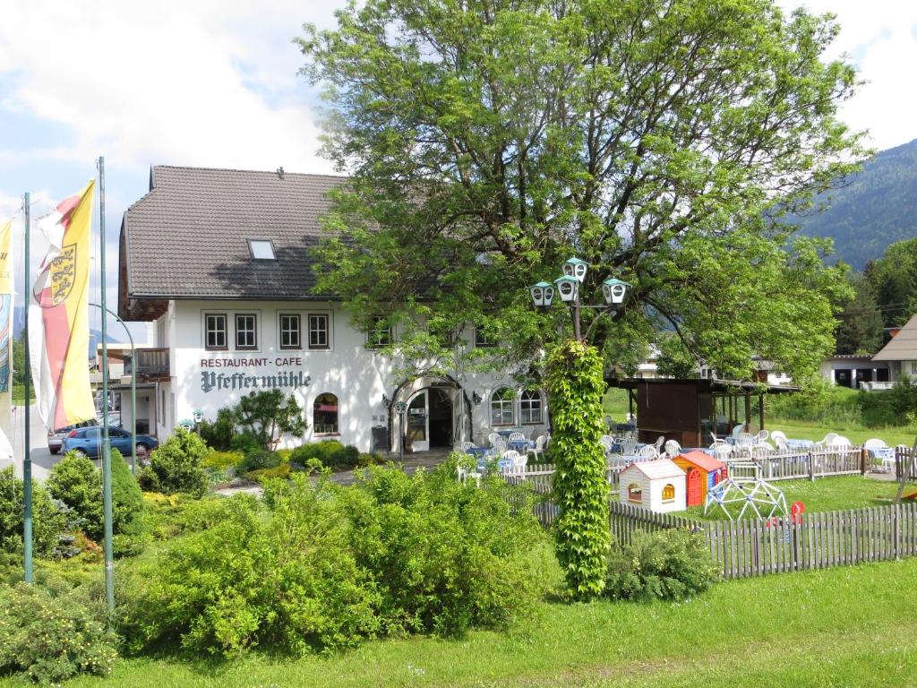 una casa con un árbol cubierto de hiedra delante de ella en Landgasthof Pfeffermühle, en Kötschach-Mauthen