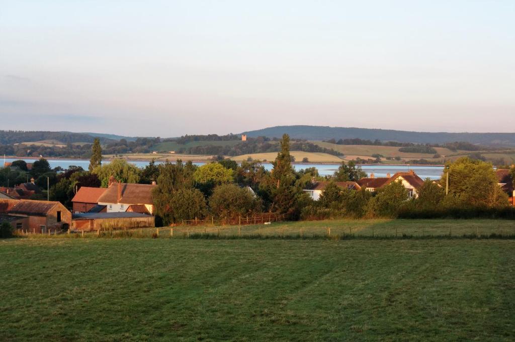 a green field with houses and a lake in the background at The Annex at Highmead in Exeter