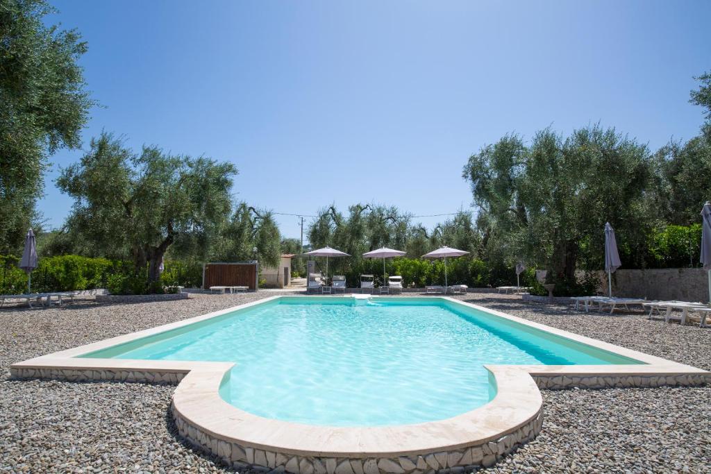a swimming pool in a yard with trees and umbrellas at Agriturismo da Mauro in Vieste