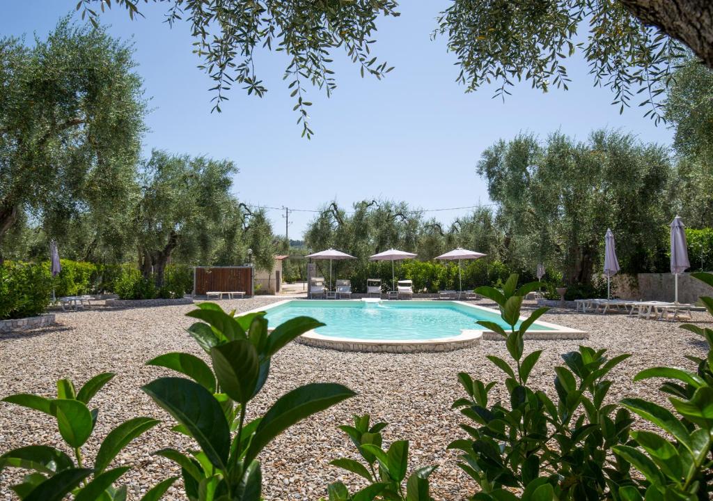 a swimming pool in a yard with trees and umbrellas at Agriturismo da Mauro in Vieste