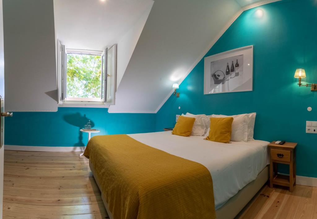 a bedroom with a bed with blue walls and a window at Casa do Vinho Sintra Guest House in Sintra