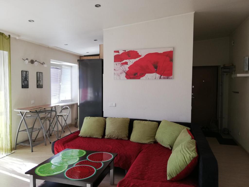 ein Wohnzimmer mit einem roten Sofa und einem Tisch in der Unterkunft Cosy Apartment in Klaipėda