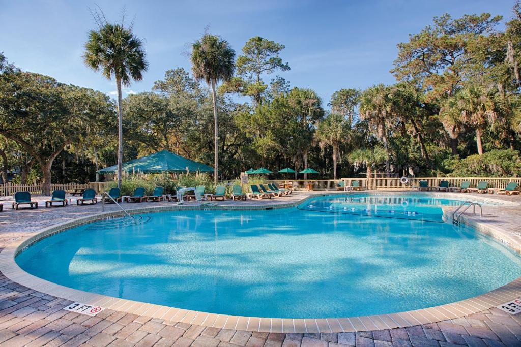 a large swimming pool with chairs and palm trees at Club Wyndham Ocean Ridge in Edisto Island