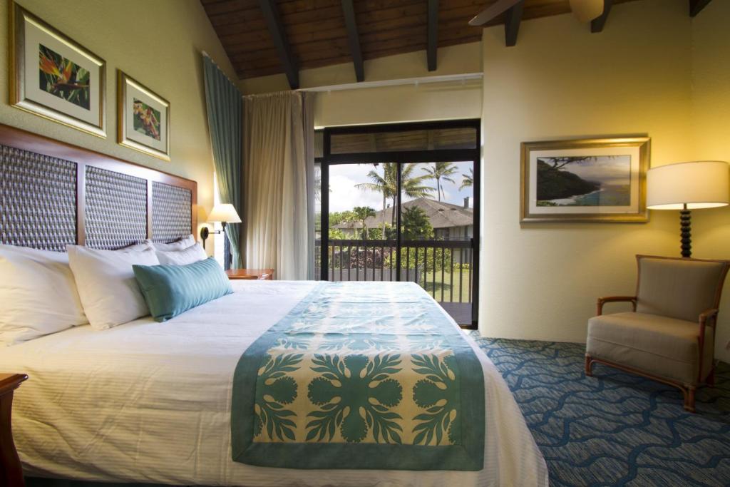 a bedroom with a bed and a chair and a window at Club Wyndham Ka Eo Kai in Princeville