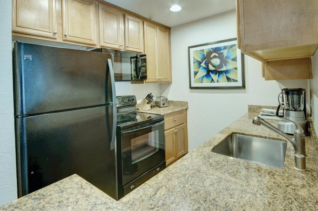 eine Küche mit einem schwarzen Kühlschrank und einer Spüle in der Unterkunft Desert Rose Resort in Las Vegas