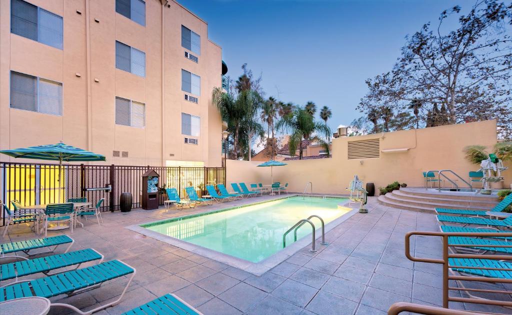 a swimming pool with blue chairs and a building at WorldMark San Diego – Mission Valley in San Diego