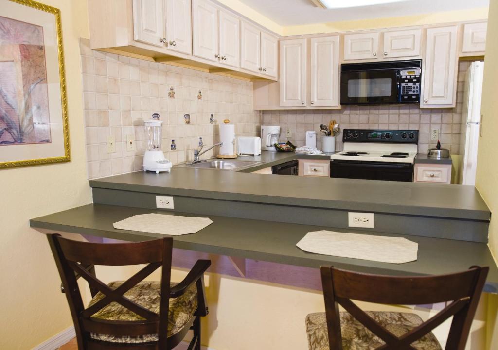 a kitchen with a counter with two chairs in it at Club Wyndham Sea Gardens in Pompano Beach