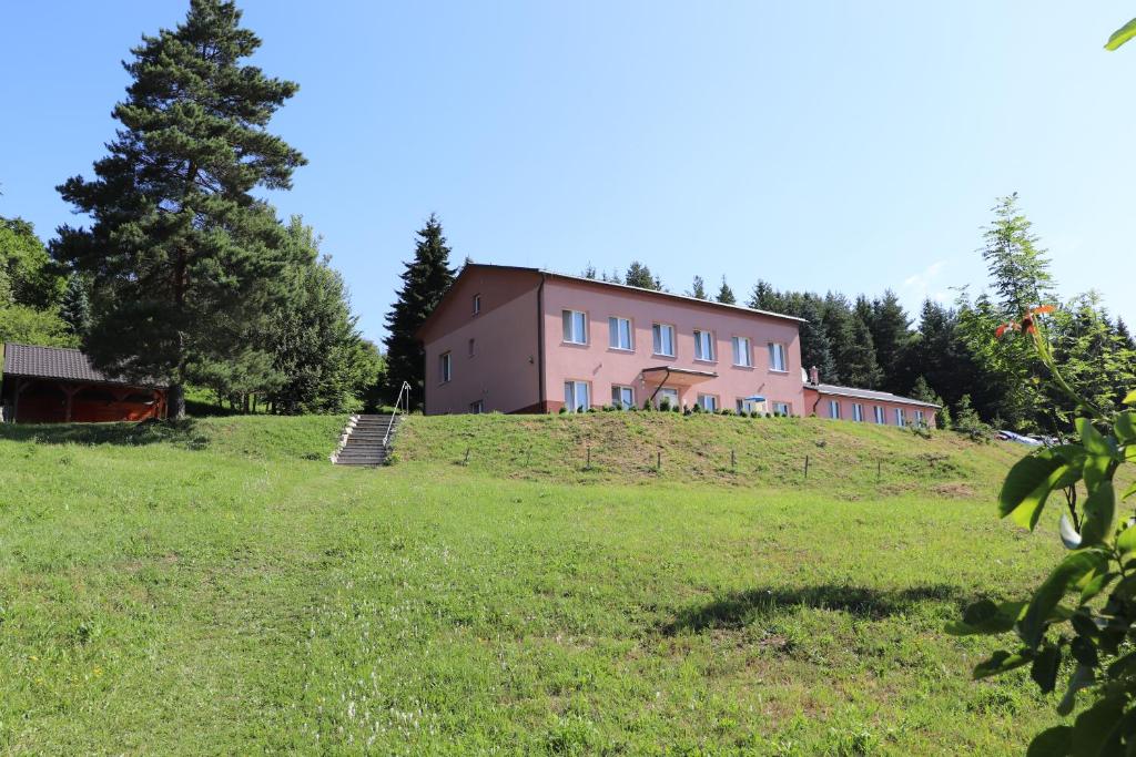 un edificio rosa en la cima de una colina con césped en Villa Žakýl, en Banská Štiavnica