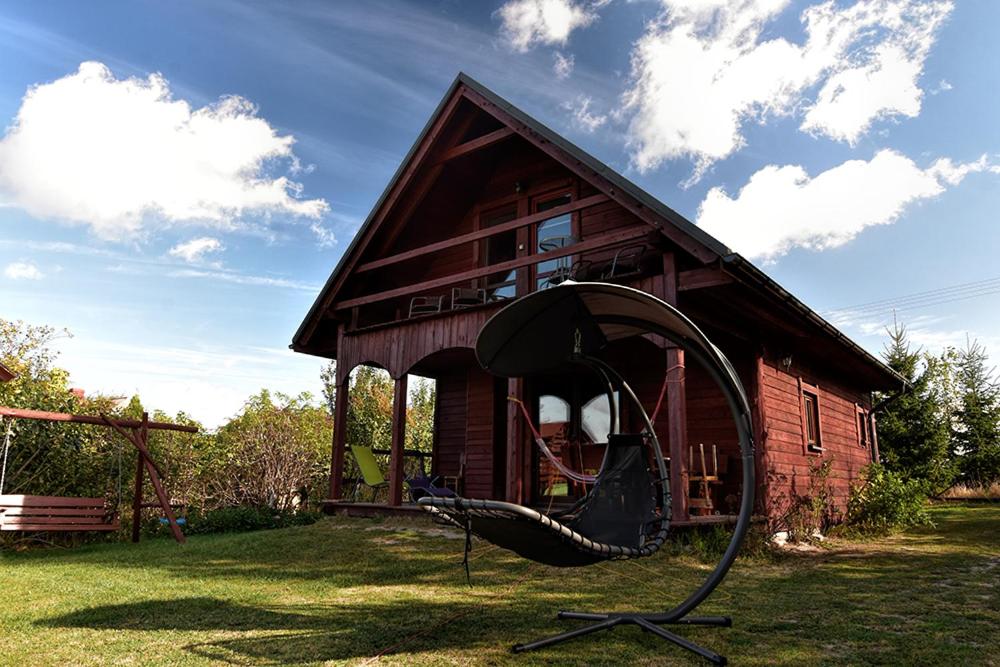 uma casa com um baloiço à frente dela em Skarlinówka em Wawrowice