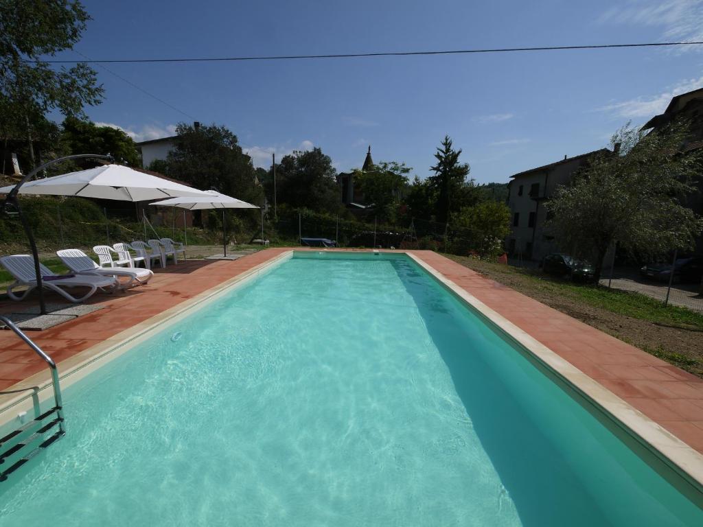 una gran piscina azul con sillas y sombrilla en Castello di Rometta Private Pool, en Fivizzano