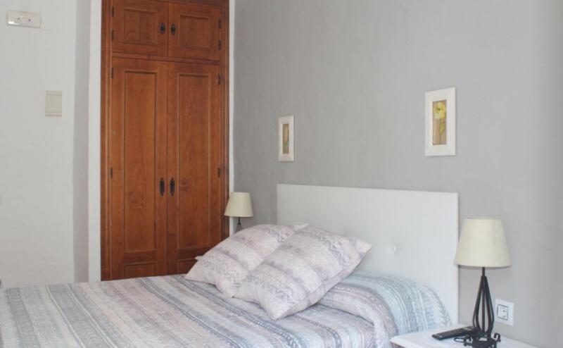 a white bedroom with a bed and a wooden door at Hostal El Espinel in Zahara de los Atunes