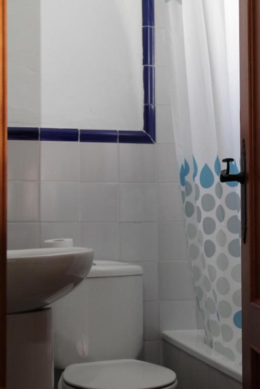 a bathroom with a toilet and a sink and a shower curtain at Hostal El Espinel in Zahara de los Atunes