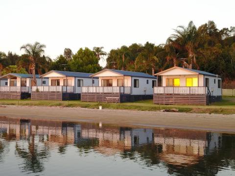 una fila de casas junto a un cuerpo de agua en Tuross Lakeside Holiday Park, en Tuross Heads