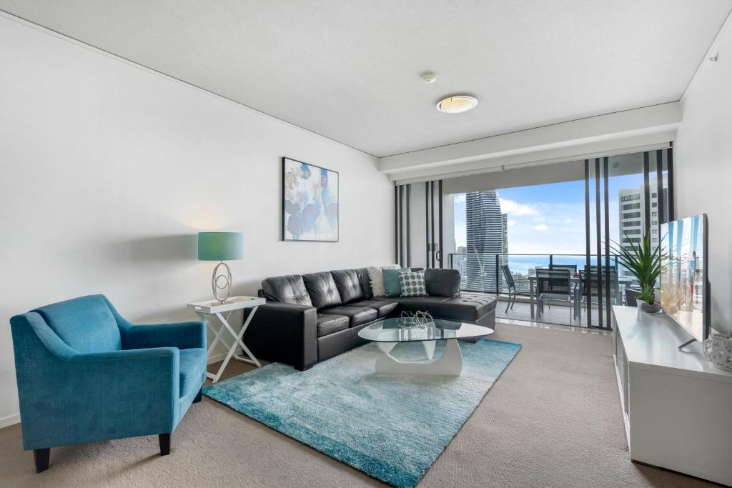 a living room with a couch and a blue chair at Sierra Grand Broadbeach - GCLR in Gold Coast