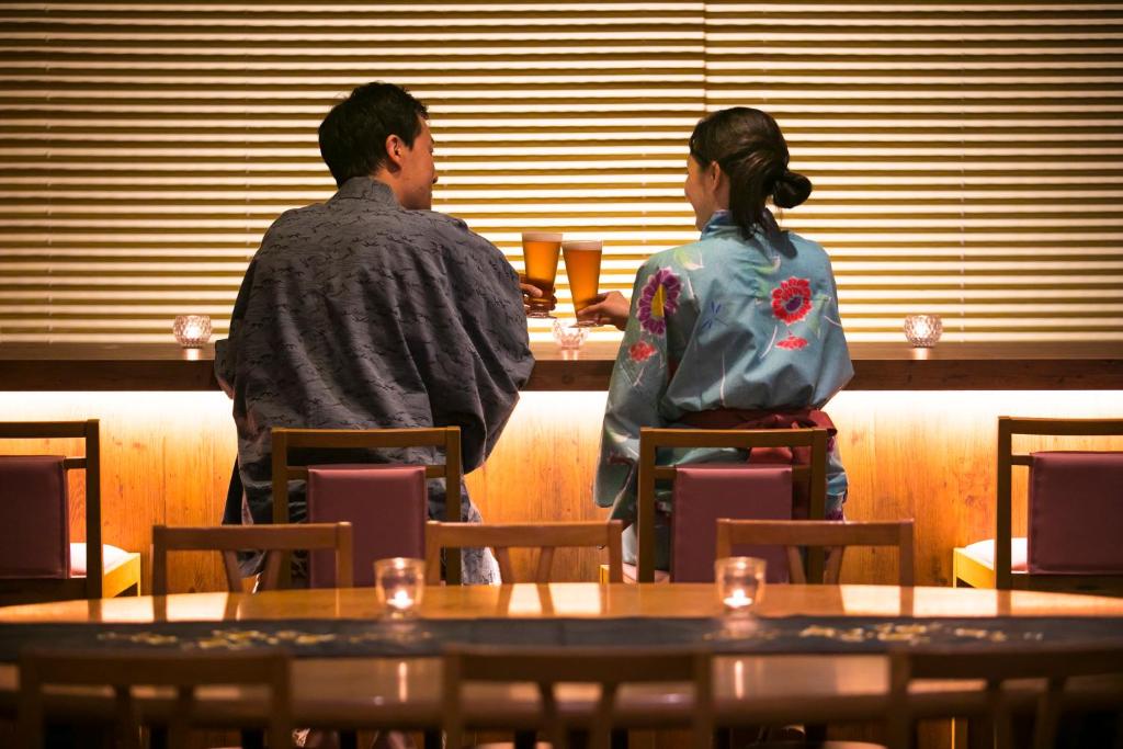 a man and a woman standing at a table at Izu atagawa Yubana mankai -Adult Only- in Higashiizu