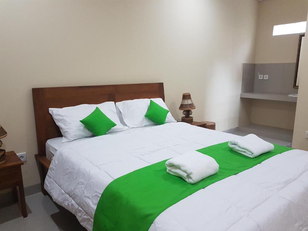 Schlafzimmer mit einem großen Bett mit grüner und weißer Bettwäsche in der Unterkunft Gusti Room in Ubud
