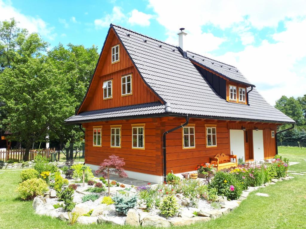 Chalupa Pomněnka في Komorní Lhotka: منزل خشبي وامامه حديقة