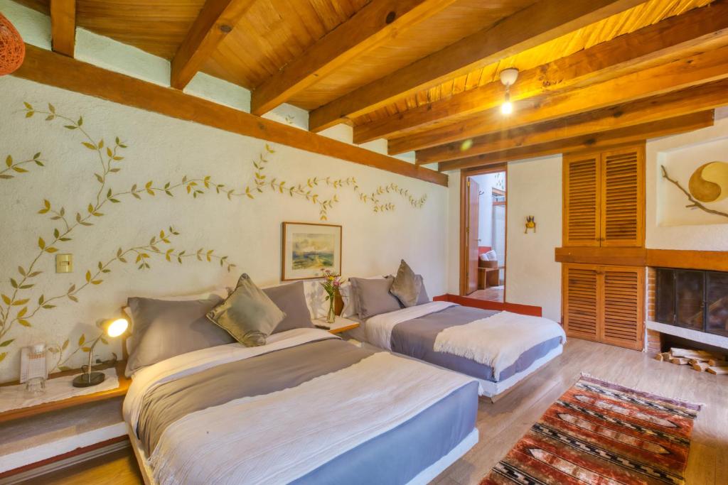 2 camas en una habitación con chimenea en La Joya del Viento, en Valle de Bravo
