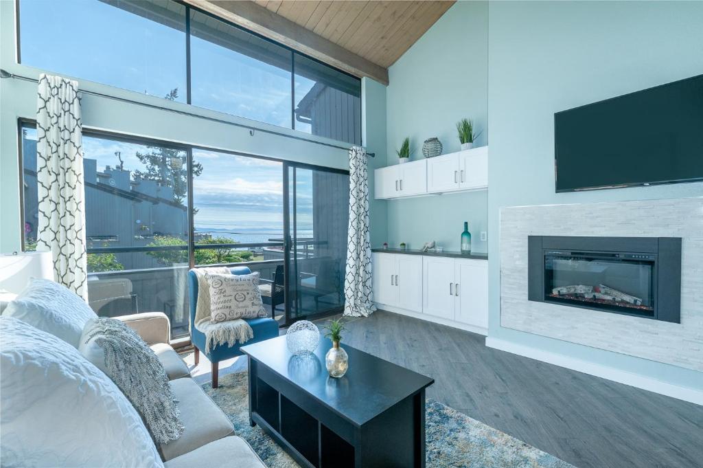 a living room with a couch and a fireplace at Birch Bay waterfront condo - Lofted layout & steps from beach in Blaine