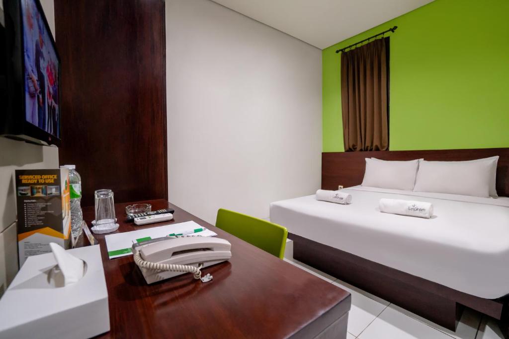 a room with a bed and a desk with a desk at LeGreen Suite Setiabudi in Jakarta