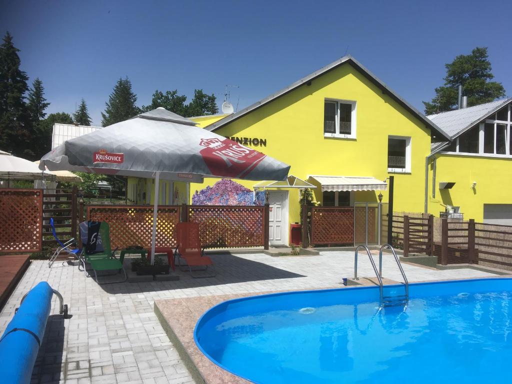 uma piscina em frente a uma casa amarela em Penzion Krásný Dvůr em Krásný Dvŭr