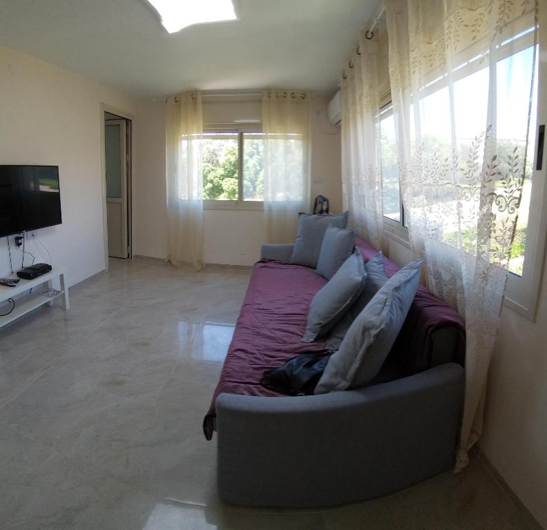 een woonkamer met een bank en een tv bij Charming beach 2 room flat in Haifa