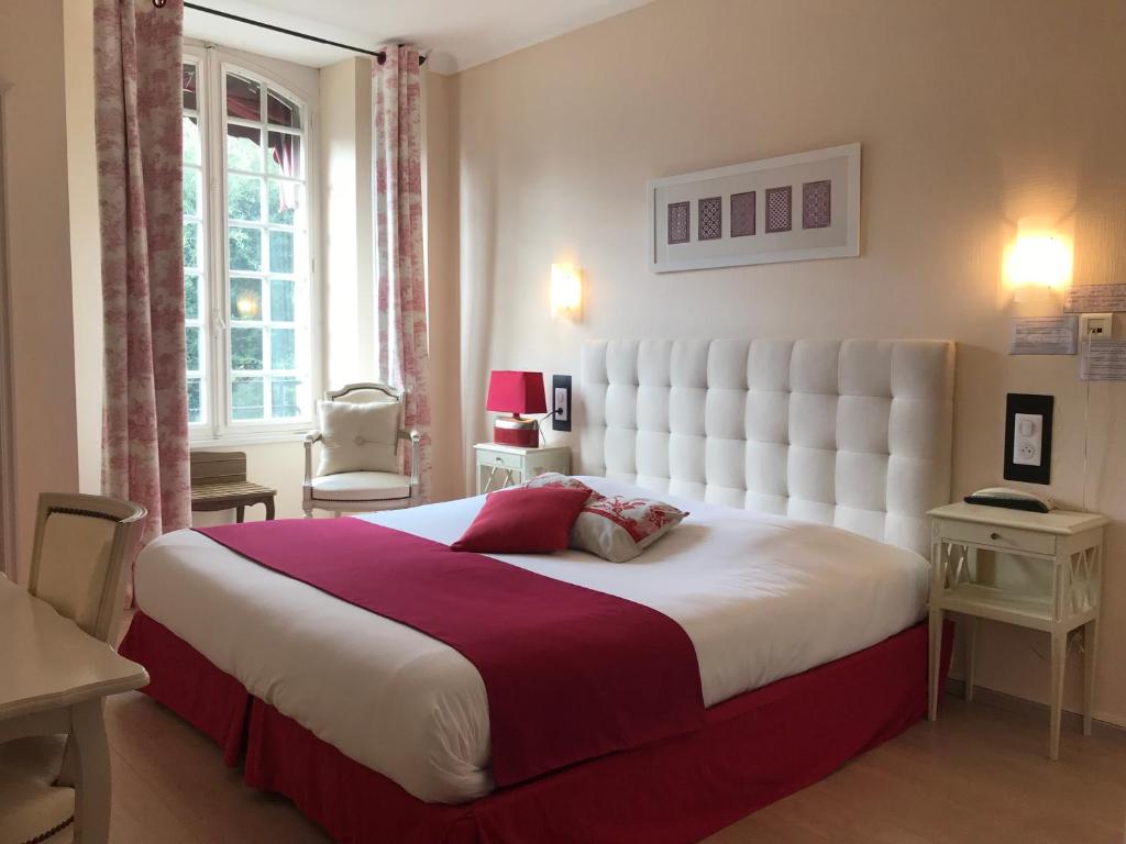 a bedroom with a large bed with a large white headboard at Hôtel Les Deux Magots in La Roche-Bernard