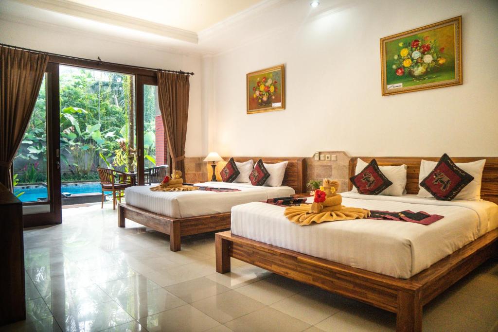 a hotel room with two beds and a couch at Alam Terrace Cottages in Ubud