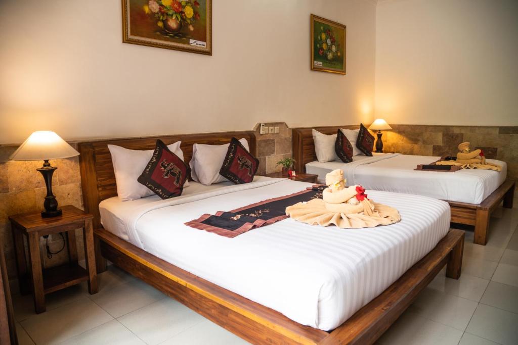 two beds in a hotel room with white sheets at Alam Terrace Cottages in Ubud