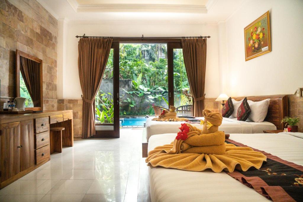 a hotel room with two beds and a bathroom at Alam Terrace Cottages in Ubud