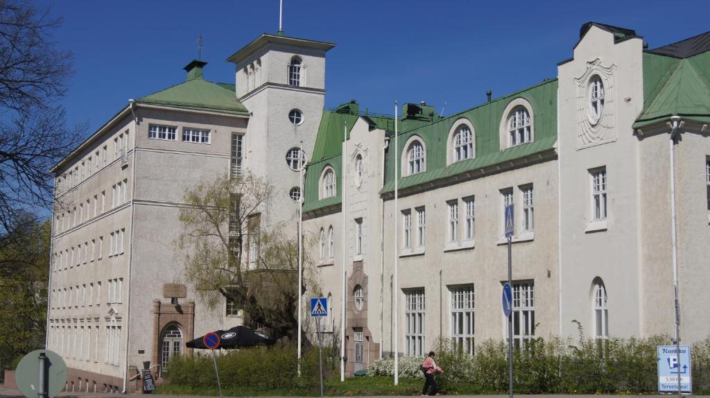 un grand bâtiment avec une tour d'horloge en face dans l'établissement Opiston Kunkku, à Lahti