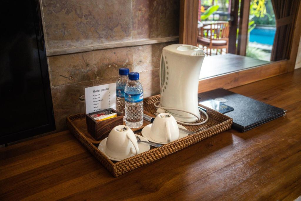 a tray with dishes and bottles of water and a blender at Alam Terrace Cottages in Ubud