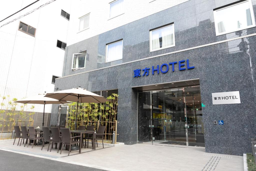 大阪市にある東方ホテルなんば元町のホテルの前にテーブルとパラソルがあります。