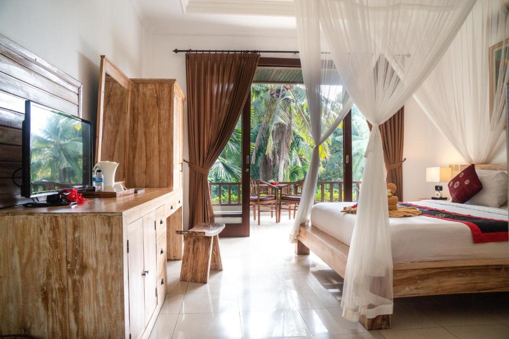 a bedroom with a bed and a large window at Alam Terrace Cottages in Ubud