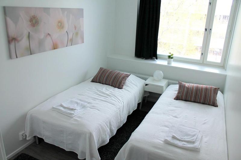 two white beds in a room with a window at Kotimaailma Apartments Joensuu - Koskikatu 11 in Joensuu
