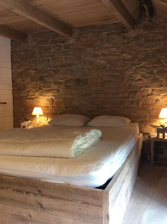 uma cama num quarto com uma parede de pedra em Petite maison d'Amelotte em Sainte-Cécile