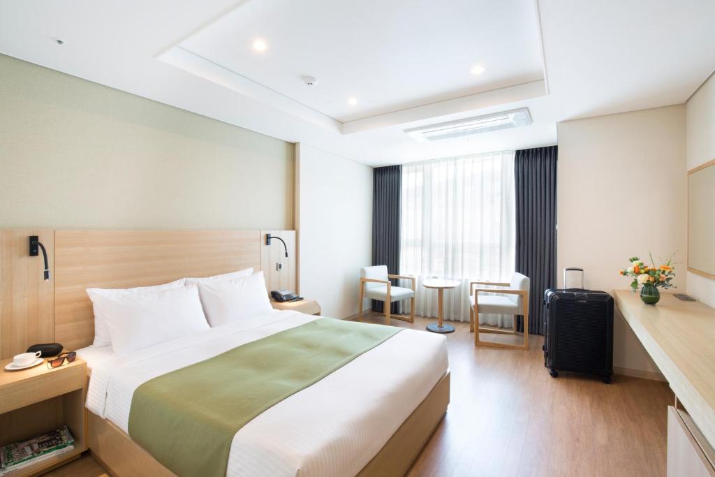 um quarto de hotel com uma cama, uma mesa e cadeiras em Crown Harbor Hotel Busan em Busan